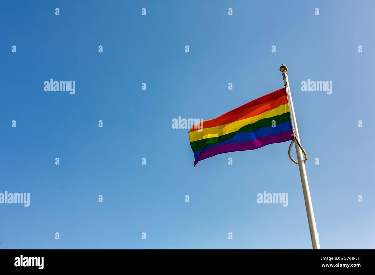 Gros plan d'un drapeau LGBT arc-en-ciel volant contre un ciel bleu clair et lumineux. Suffolk Pride. Concept de la liberté de bonheur amour de même-sexe couple Banque D'Images