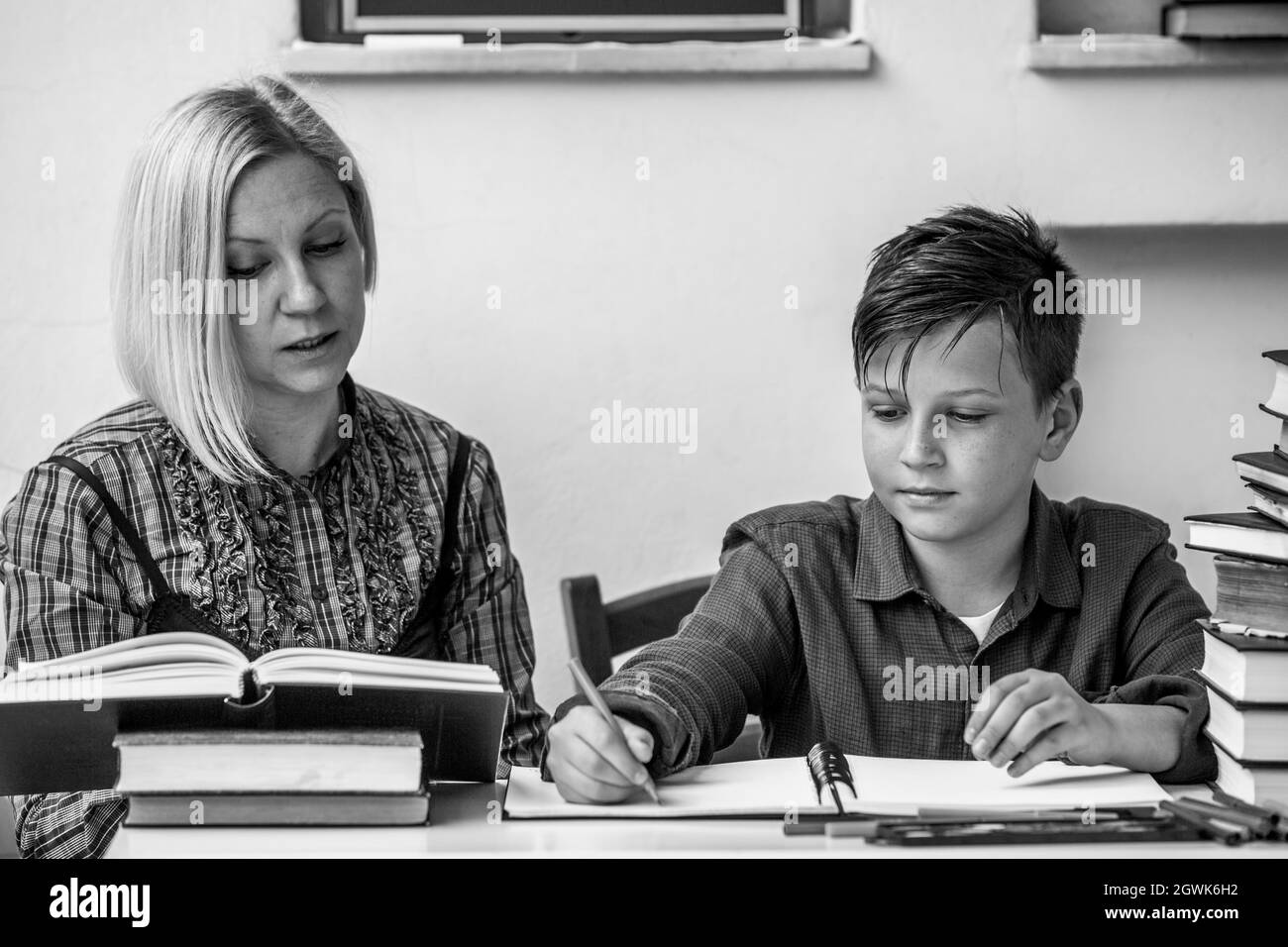 Peu d'étudiant pendant les devoirs avec l'aide d'un tuteur. Photo en noir et blanc. Banque D'Images