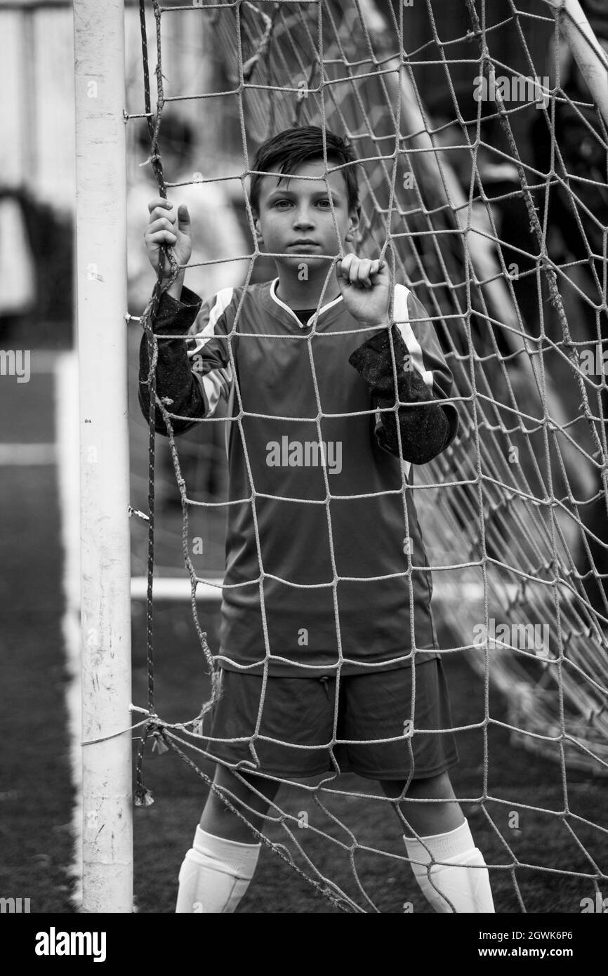 Un joueur de football de garçon près des portes du stade. Photo en noir et blanc. Banque D'Images