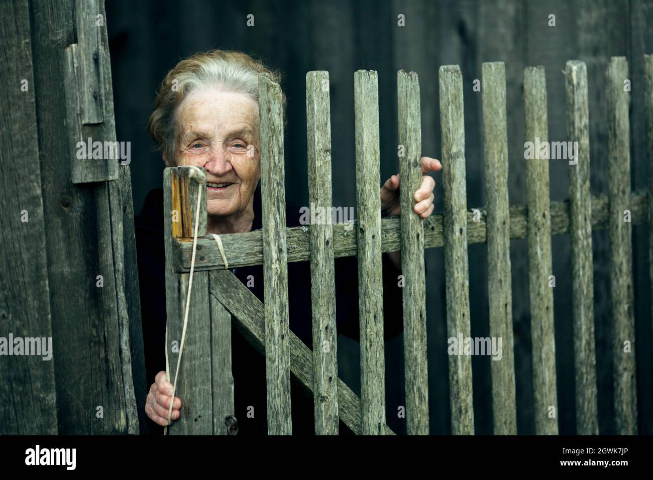 Portrait d'une vieille femme dans le village près d'une clôture en bois. Banque D'Images
