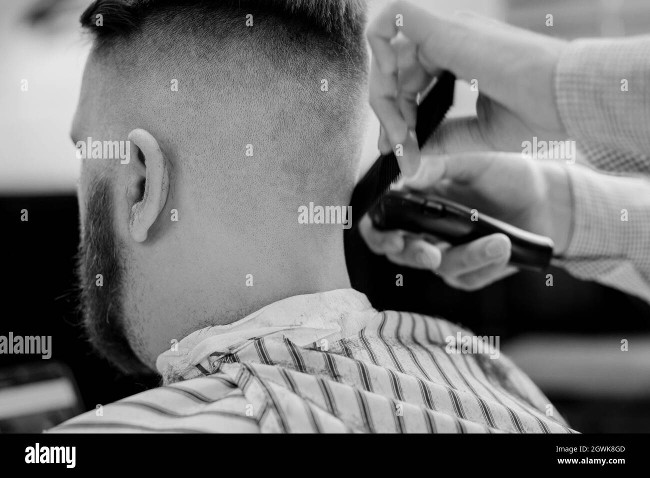 Coiffeur tondeuse cheveux sur homme dans barbershop. Coiffeur professionnel couper les cheveux avec la machine de haveuse électrique sur Guy. Photo noir et blanc Banque D'Images