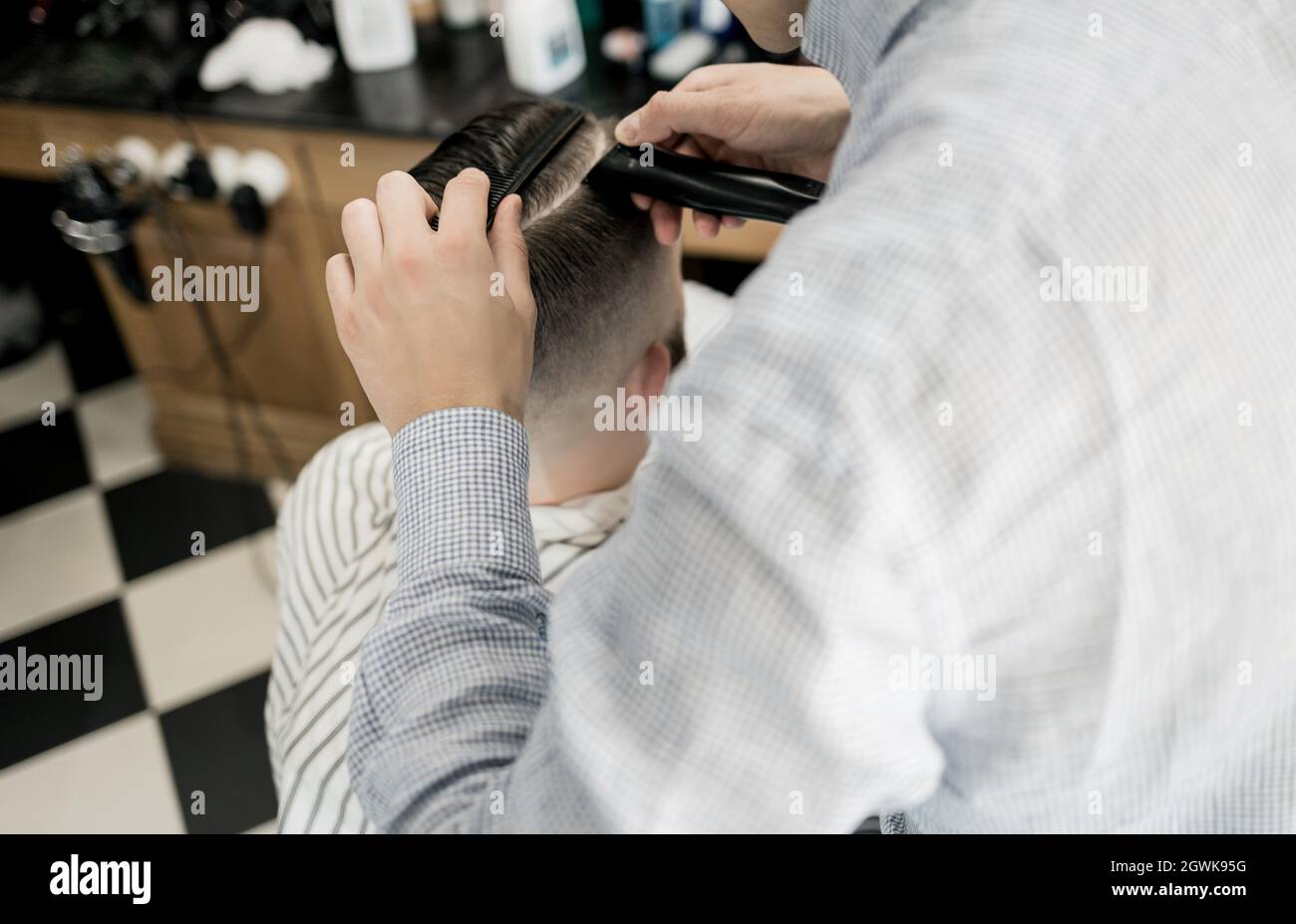 En créant un gros plan de la coupe de cheveux d'un homme, un coiffeur coupe ses cheveux. Coiffeur et travail sur les cheveux du client. Arrière-plan. Concept de salon de coiffure. Hommes Banque D'Images