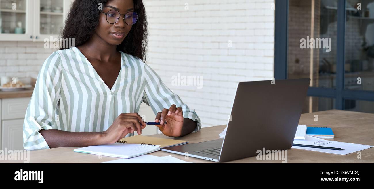 Jeune étudiant afro-américain intelligent au bureau avec des papiers et un ordinateur portable. Banque D'Images