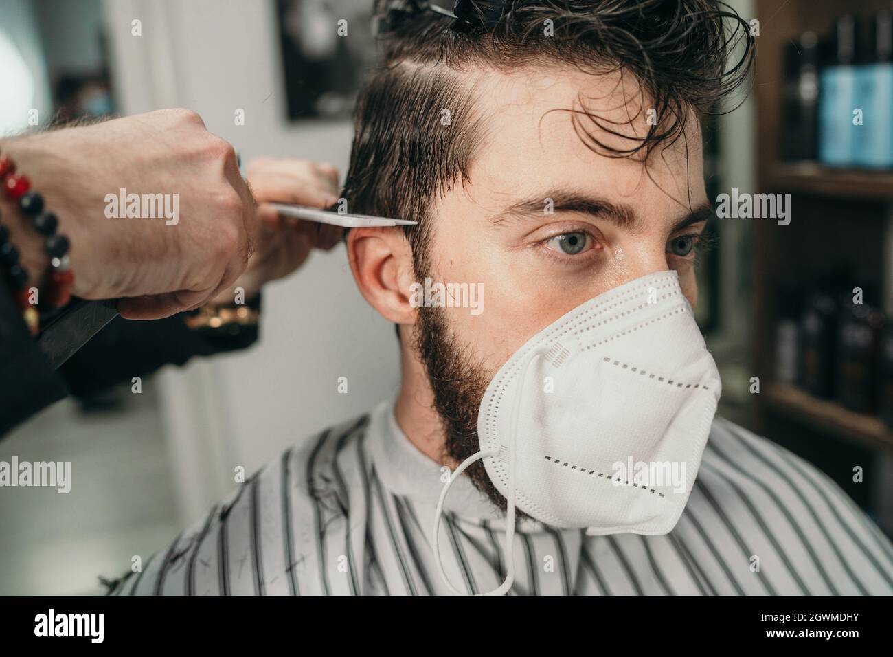 Coiffeur masculin coupe de cheveux à Un jeune homme barbu portant Un masque  facial en raison du coronavirus Photo Stock - Alamy