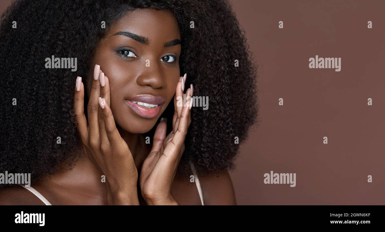 Jeune fille de beauté noire touchant le visage isolé sur brun. Portrait de tête. Banque D'Images