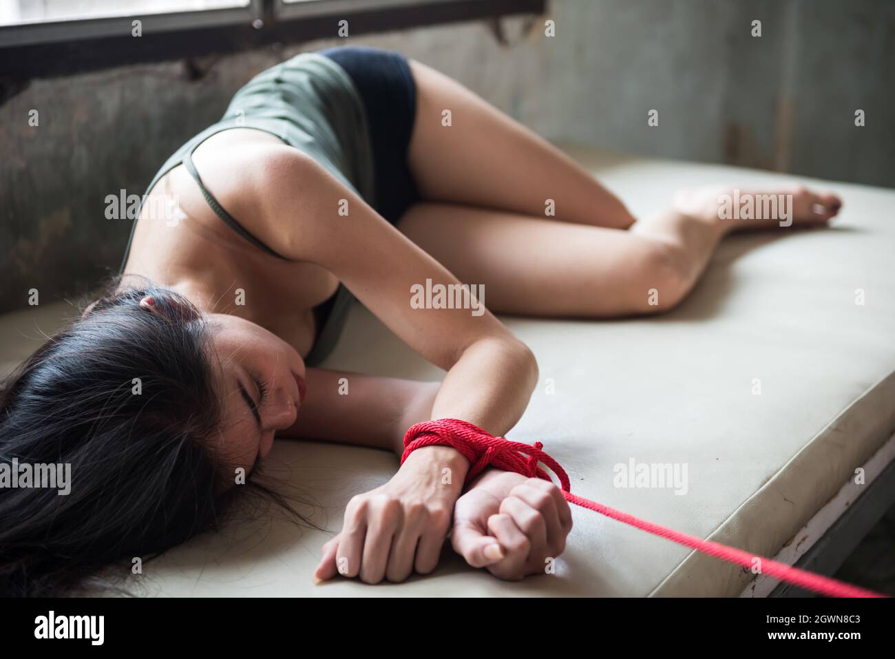 Triste jeune femme otage couché sur le lit et attaché par la corde rouge  dans la maison d'abandon.Victime d'enlèvement de femme Photo Stock - Alamy