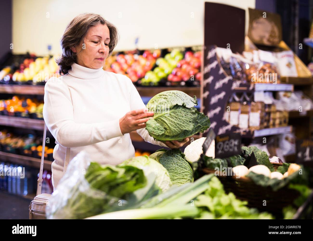 Femme âgée choisissant le chou dans la section végétale du magasin Banque D'Images