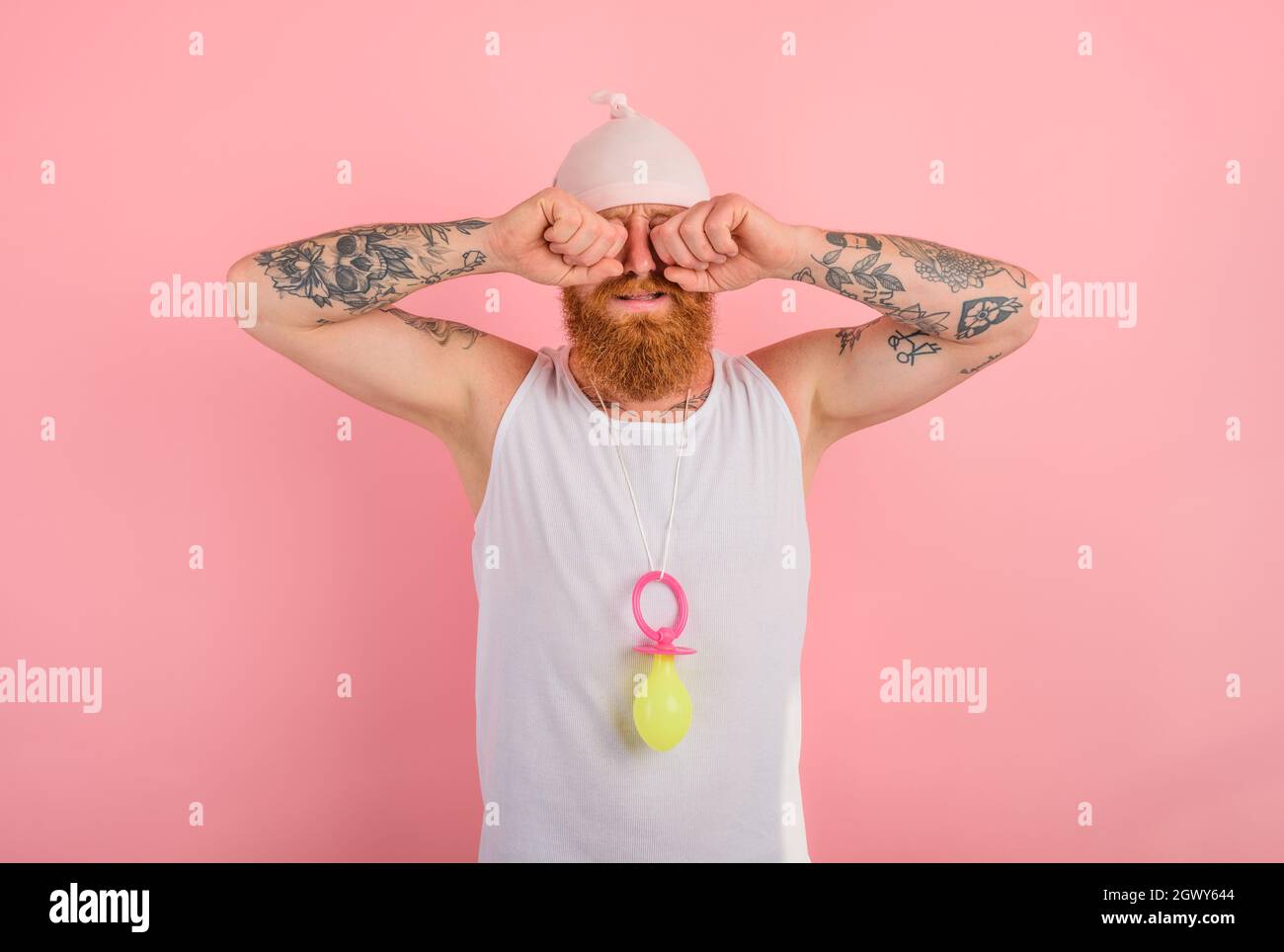 Pleurer l'homme avec la barbe et tatouages agit comme un petit nouveau-né Banque D'Images