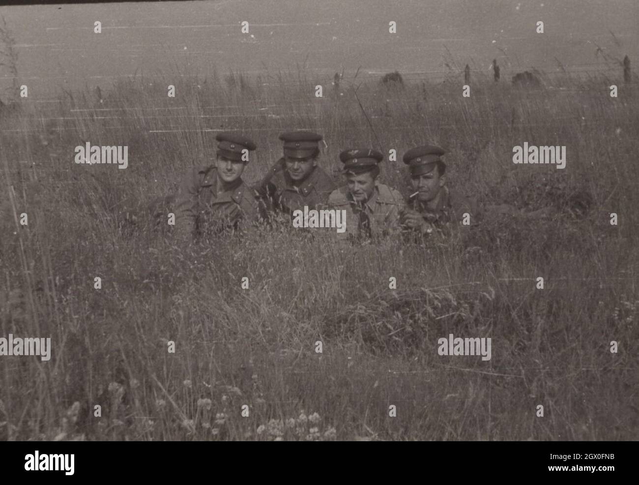 Vintage / Retro armée / militaire photo quatre officiers sont en train de poser au milieu d'un champ. Peut-être est-ce une pratique d'observation mais que pourquoi sont-ils si visibles avec des chapeaux et de la cigarette ( fumer) période des années 1960. Hongrie. Source : photo originale Banque D'Images