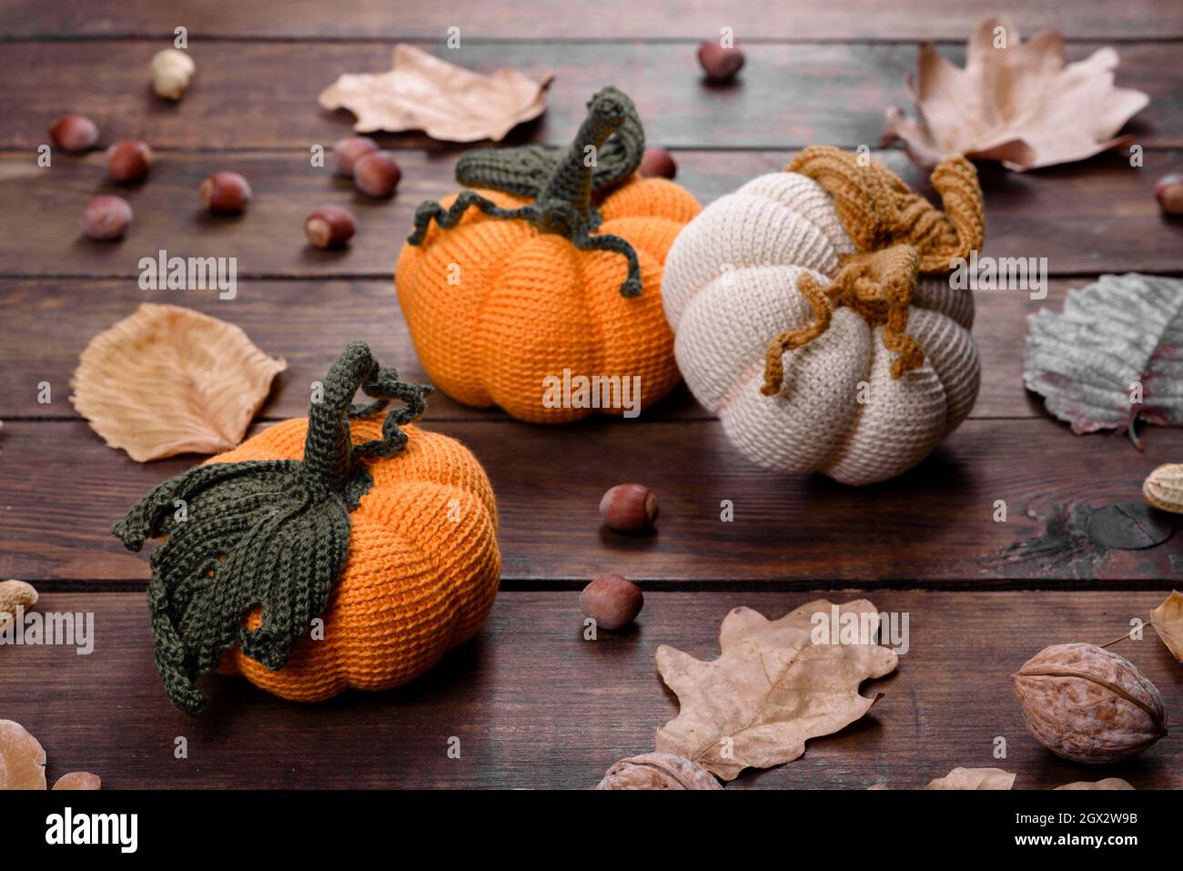 Artisanat automne encore la vie: Citrouilles tricotées et feuilles sur fond de bois. Décoration Halloween et Thanksgiving Banque D'Images