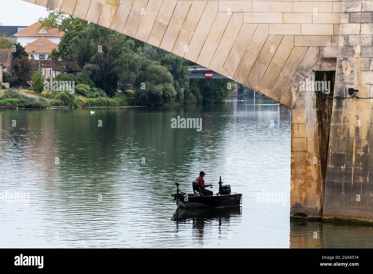 Un pêcheur dans sa ligne de bateaux de pêche sur la rivière Saône, sous le pont Saint Laurent à Chalon-sur-Saône, France. Banque D'Images