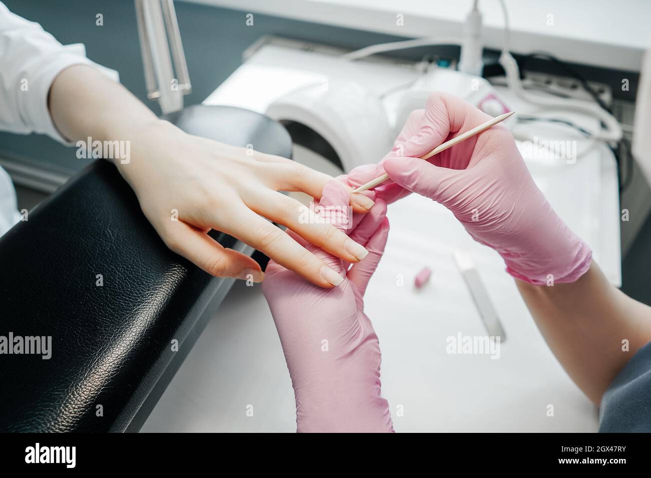 Une jeune femme se fait manucure dans un salon de beauté. Manucure faire manucure avec des gants roses. Banque D'Images