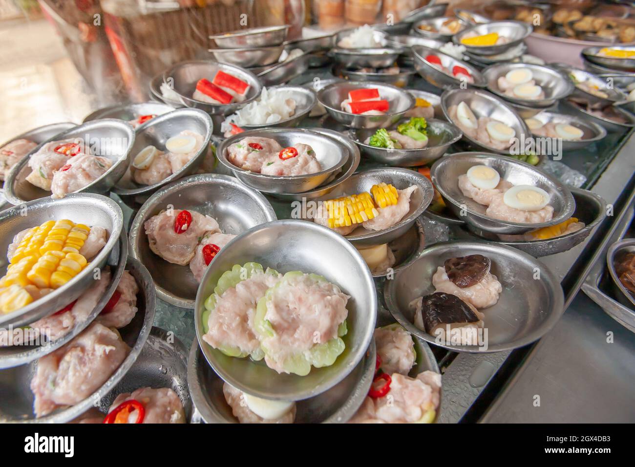 Une variété de boulettes de banderoles Dim Sum servies sur de petites assiettes en acier inoxydable dans un restaurant chinois-thaïlandais local à Betong, Yala, Thaïlande. Banque D'Images