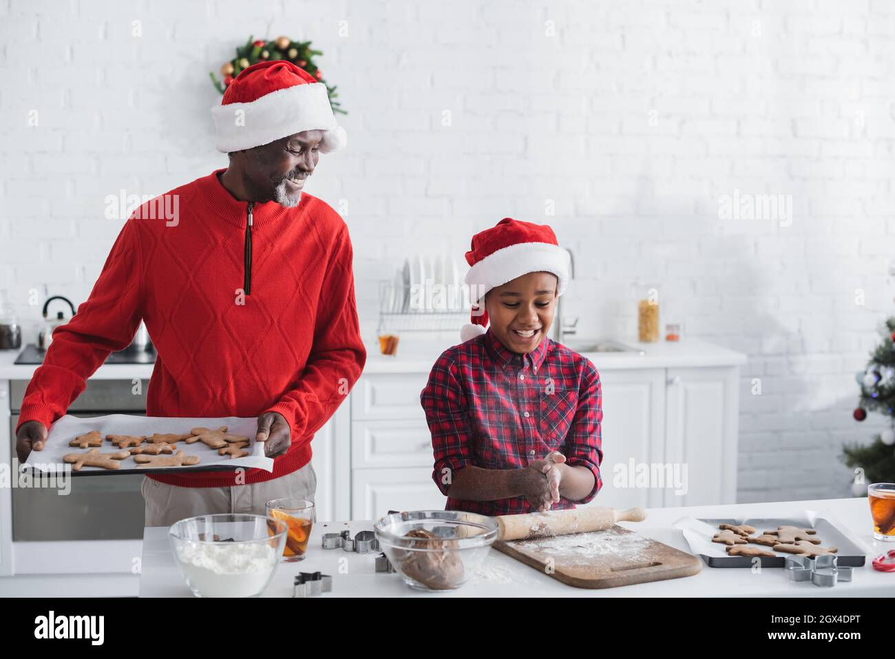 bon homme afro-américain tenant une plaque de cuisson avec des biscuits de noël près de petit-fils Banque D'Images