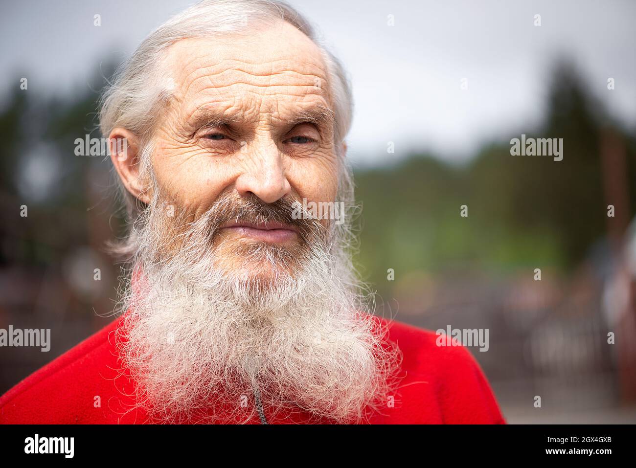 Ancienne génération. Portrait d'un homme barbu senior positif debout à l'extérieur et regardant l'appareil photo avec un regard triste Banque D'Images