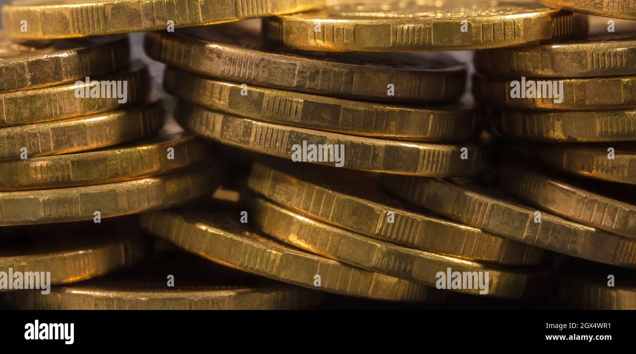 Pièces de monnaie jaunes, avec des encoches sur le sout, macro sur fond sombre Banque D'Images