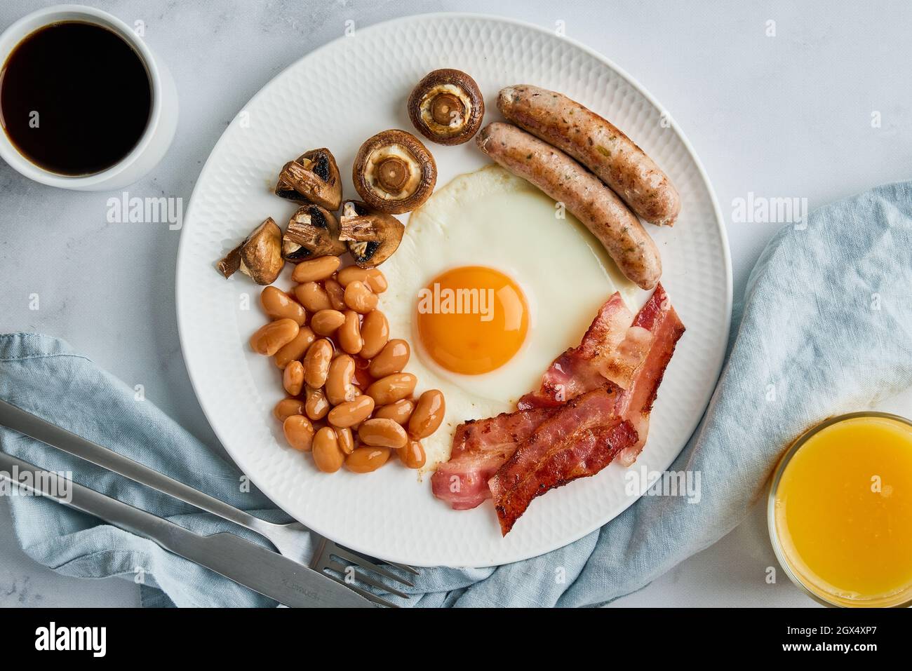 Petit déjeuner anglais classique avec œufs, saucisses, becon, haricots, champignons, café et jus d'orange Banque D'Images