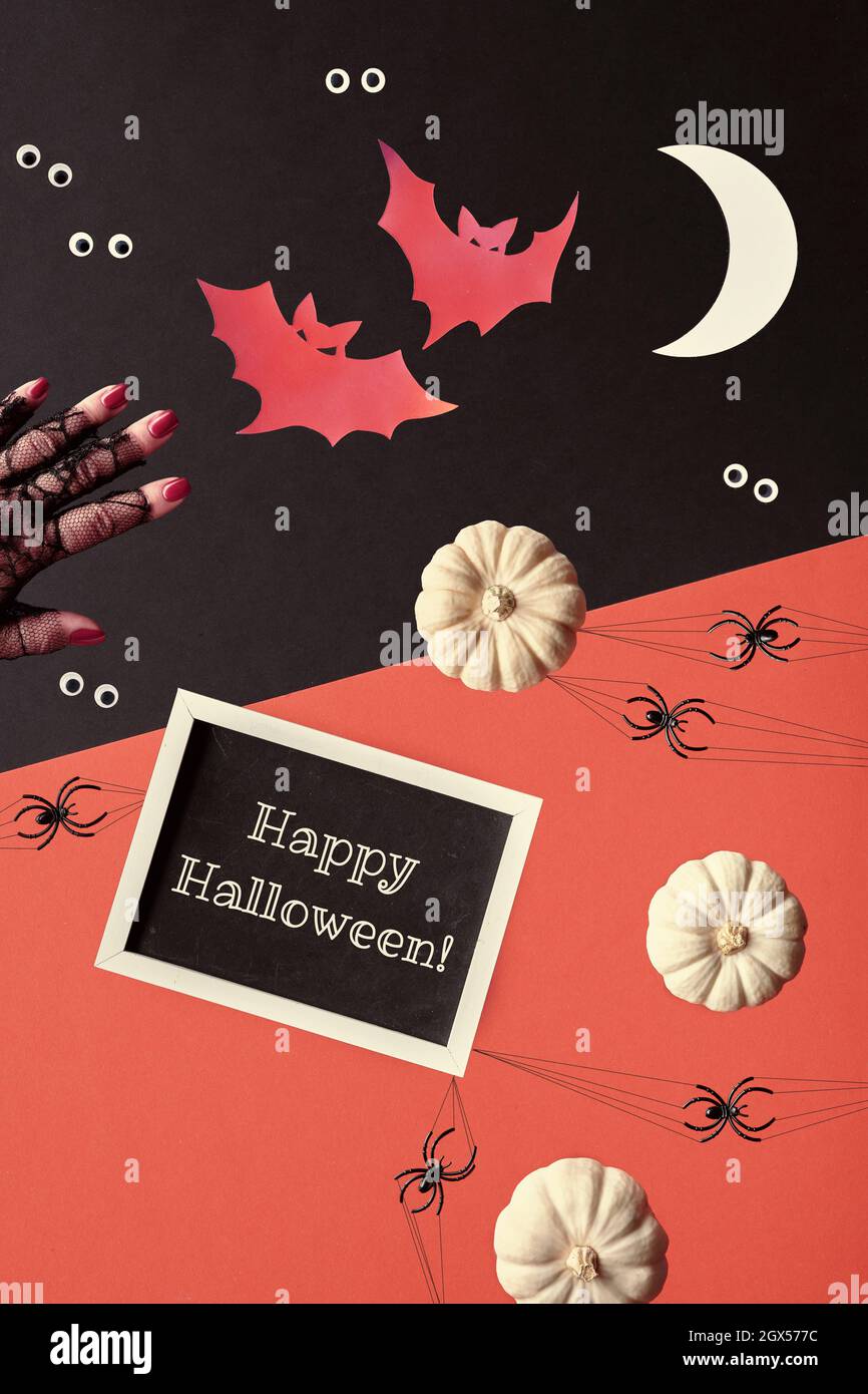 Résumé composition Halloween en rouge, noir et blanc. Texte Happy Halloween sur tableau noir. Silhouettes en papier de chauves-souris, croissant de lune. Yeux de bonne surprise Banque D'Images