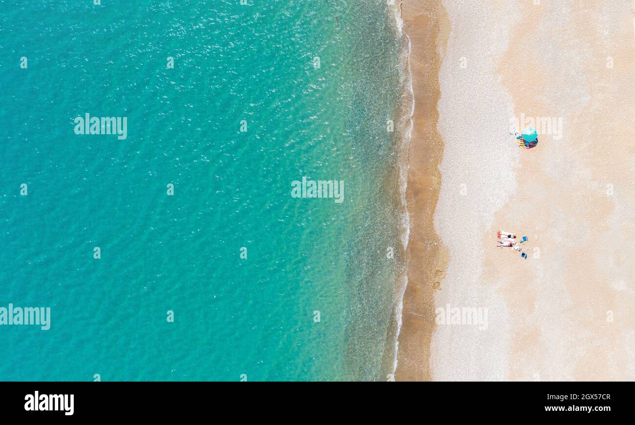 Plage de sable avec peu de personnes prenant le bain de soleil et mer calme. Vue aérienne directement au-dessus, espace de copie Banque D'Images