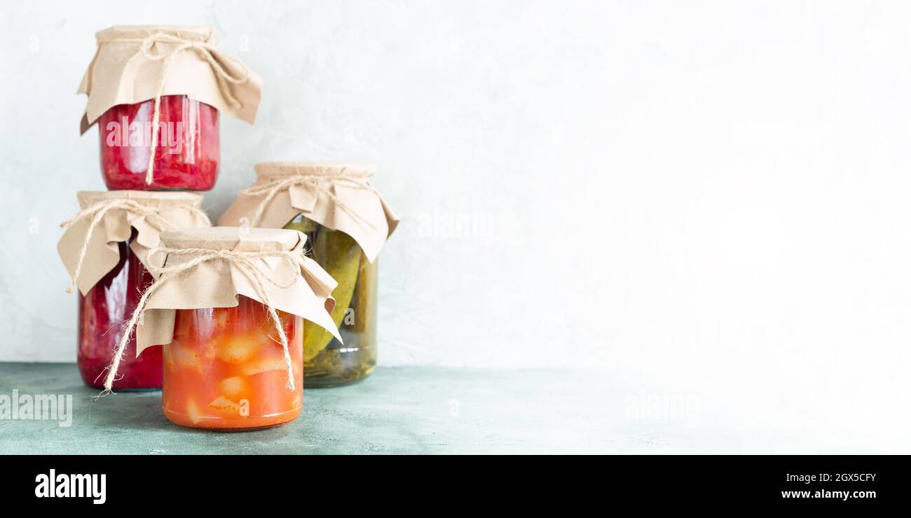 Cornichons, légumes conservés dans des pots en verre sur fond vert clair avec espace de copie. Préparations faites maison, stockage des aliments. Emballage écologique Banque D'Images