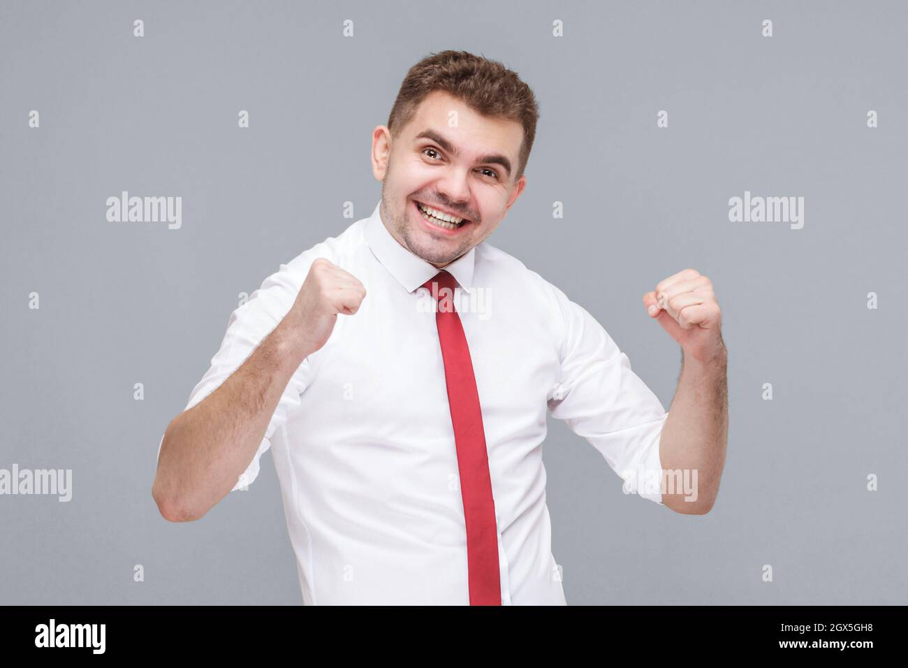 Oui, je l'ai fait. Portrait de jeune beau heureux homme réussi en chemise blanche et cravate debout et célébrant sa victoire. Intérieur isolé sur fond gris. Banque D'Images Oui, je l'ai fait. Portrait de jeune beau heureux homme réussi en chemise blanche et cravate debout et célébrant sa victoire. Intérieur isolé sur fond gris. Banque D'Images