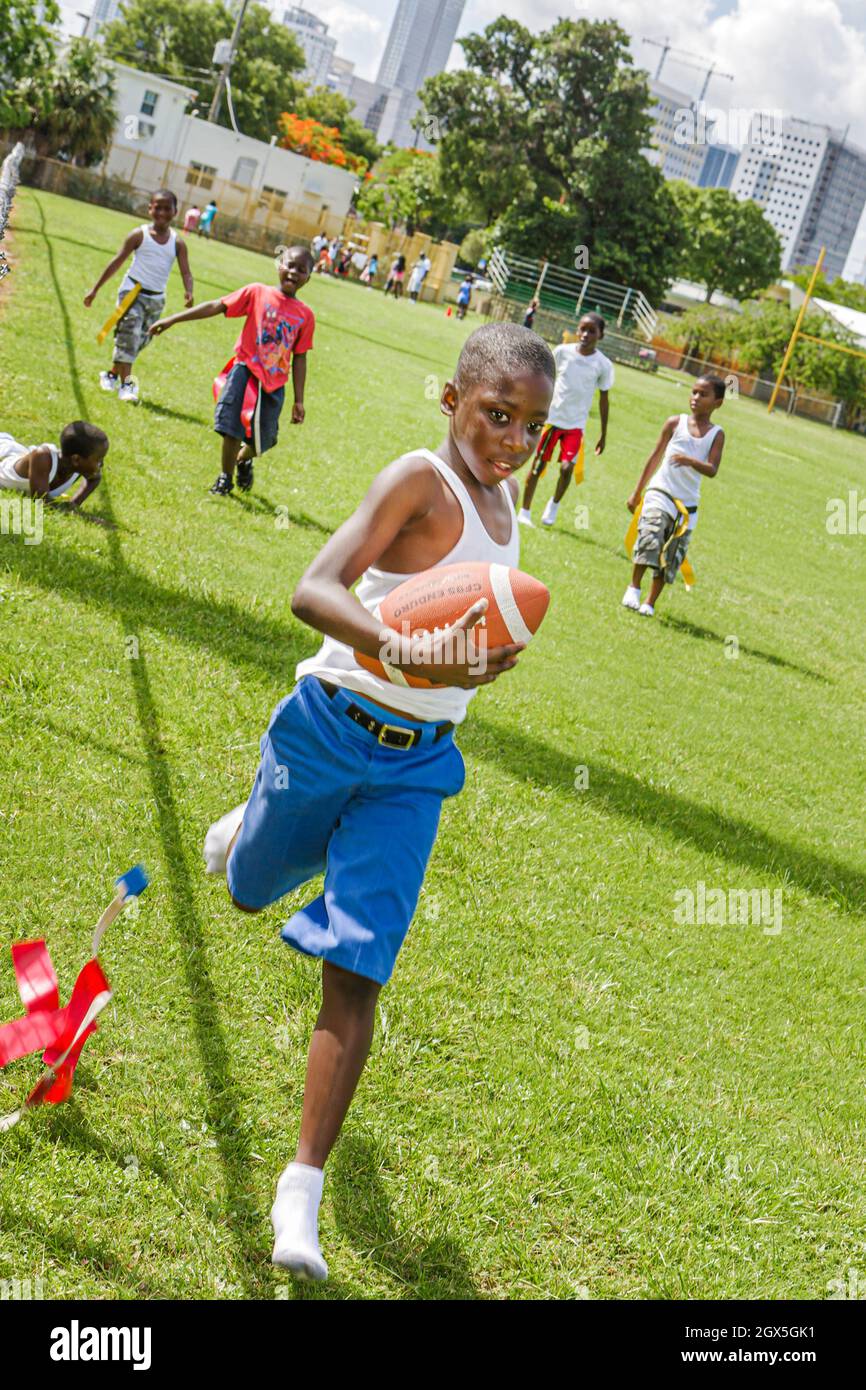 Miami Florida, Overtown Youth Centre, programme communautaire, camp d'été de la ville intérieure drapeau football, Black mâle garçons enfants jouant à la course Banque D'Images