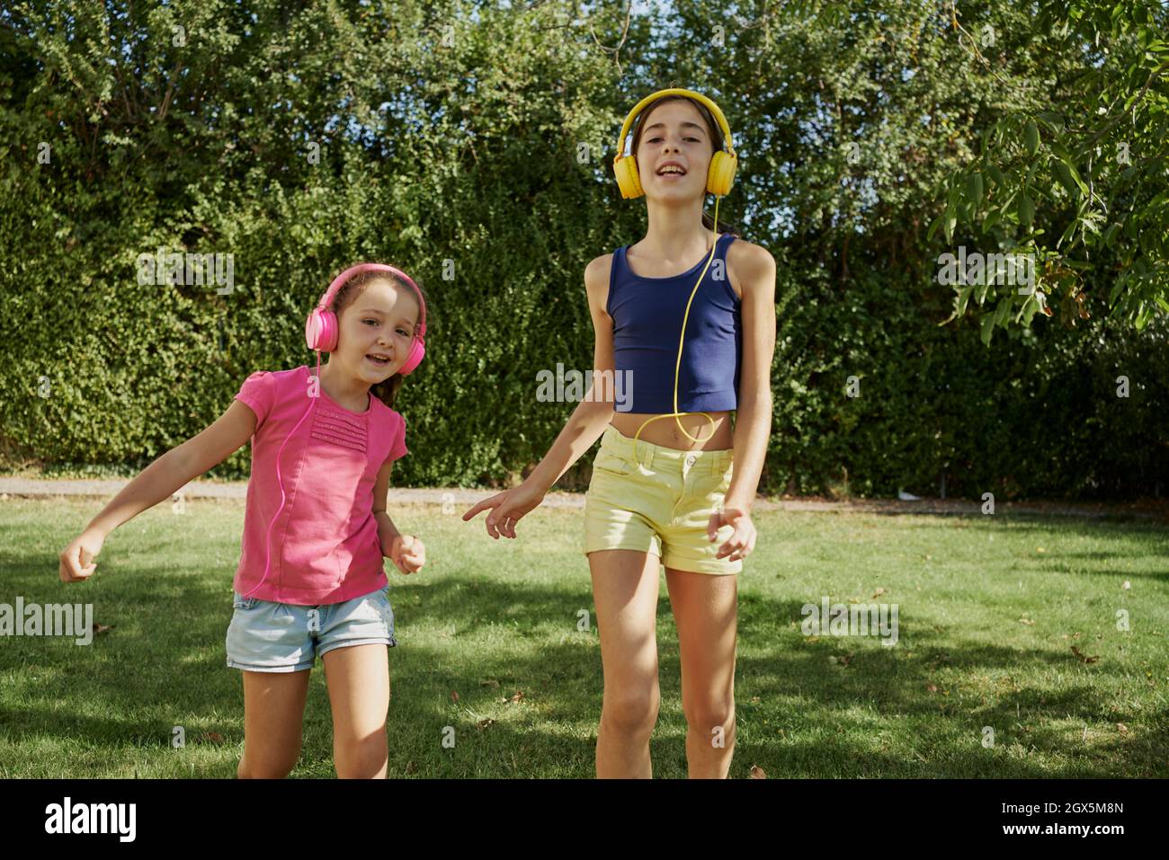 deux filles dansent une chanson en utilisant leur casque à l'arrière-cour. Deux filles dansent et jouent à l'arrière-cour. Banque D'Images