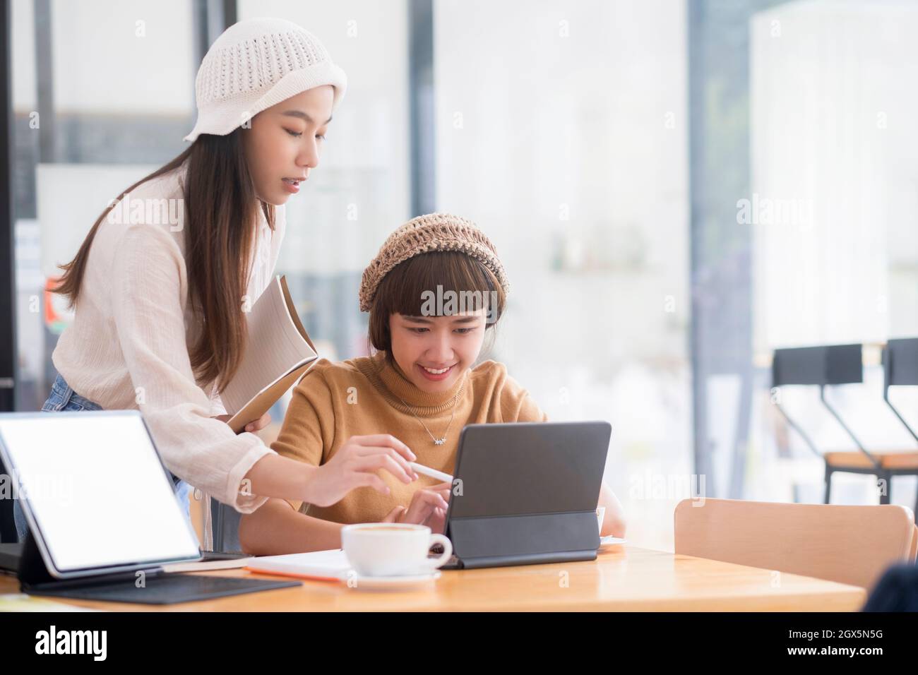 Photo de deux jeunes femmes travaillant ensemble sur tablette numérique. Les femmes cadres créatifs réunis dans le cadre d'un office à l'aide de tablet pc et de sourire. Banque D'Images
