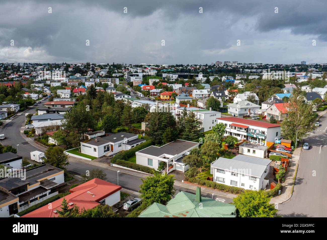 Vue aérienne des maisons de banlieue et des arbres verts situés près de la route asphaltée contre le ciel nuageux le jour d'été ennuyeux en ville. Banque D'Images