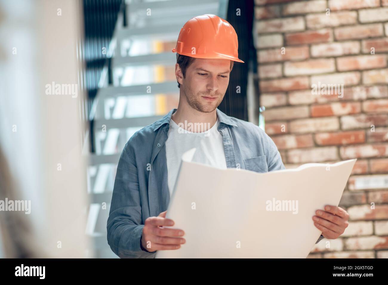 Homme travaillant avec le plan de construction au composant de bâtiment Banque D'Images
