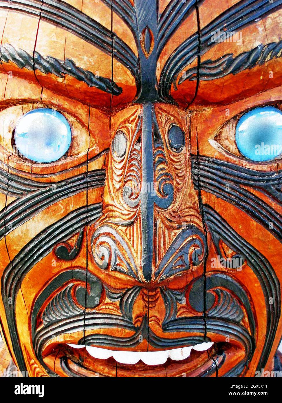 Un toi whakairo en bois sculpté d'un guerrier maori avec le visage entier Moko et les yeux d'ormeau. Banque D'Images