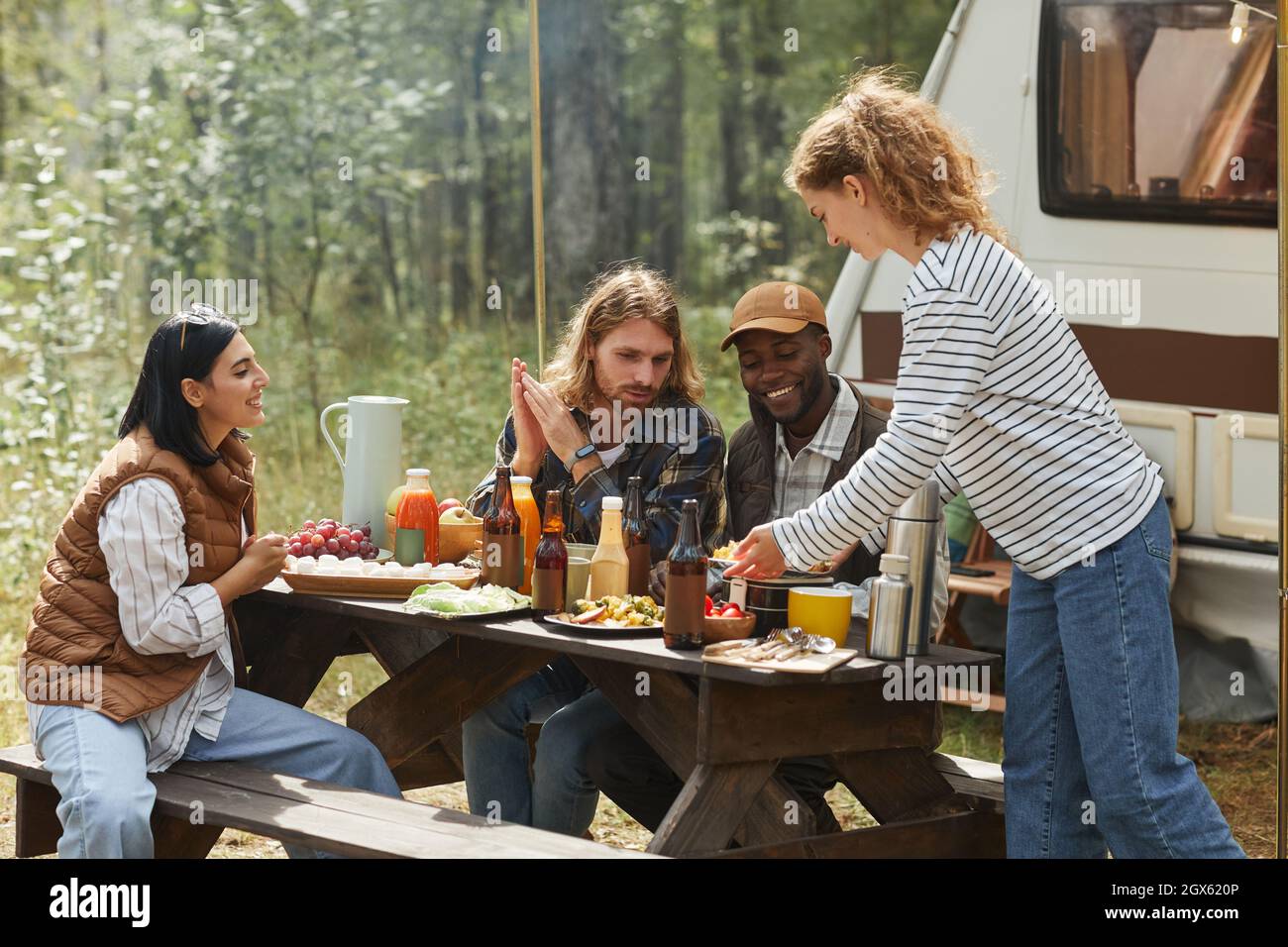Divers groupes d'amis qui profitent d'un pique-nique en plein air au camping avec une camionnette Banque D'Images