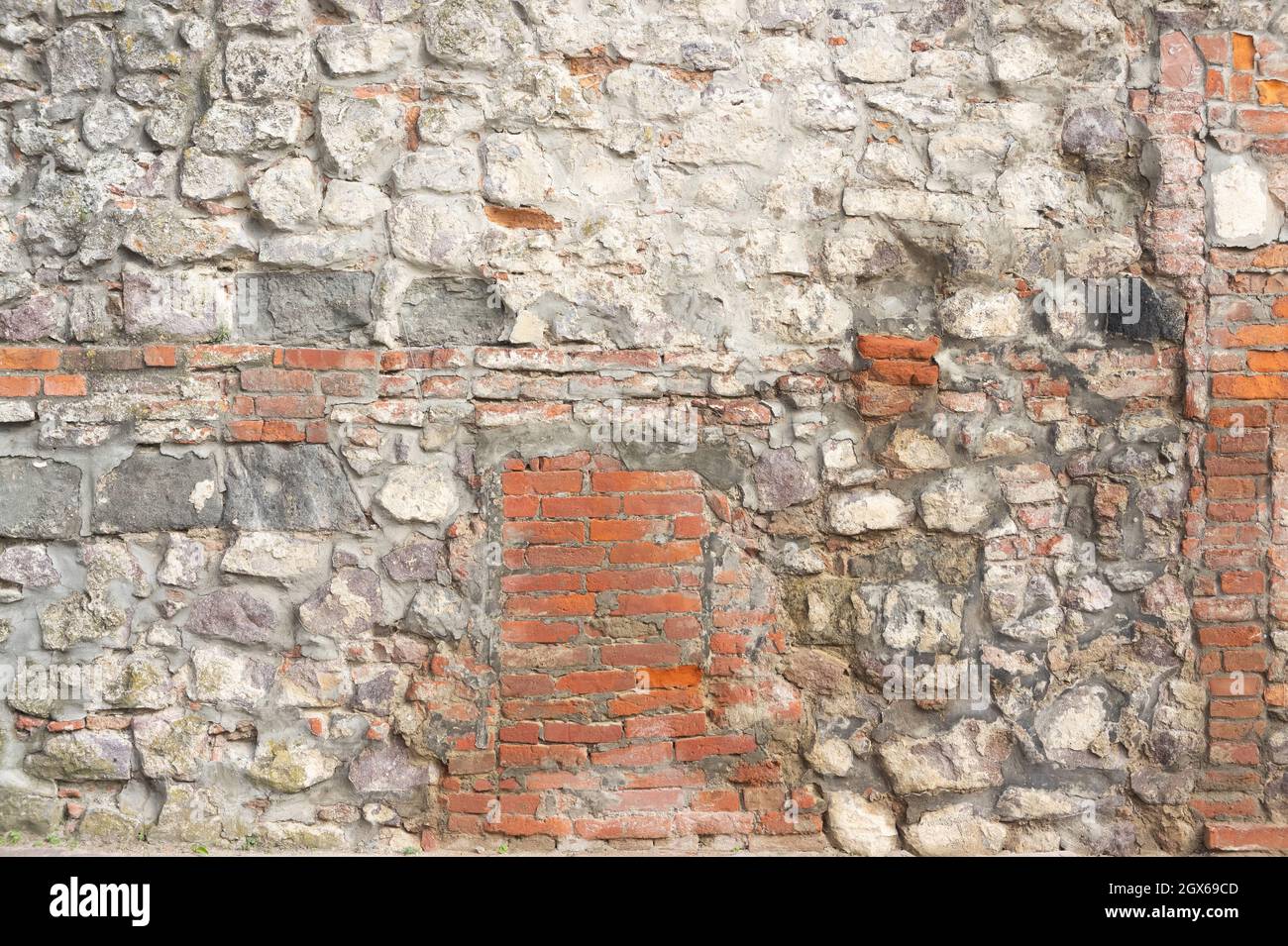 mur de pierre. la brique rouge et la grande pierre blanche sont empilées dans un ordre différent. fragment d'un ancien château Banque D'Images