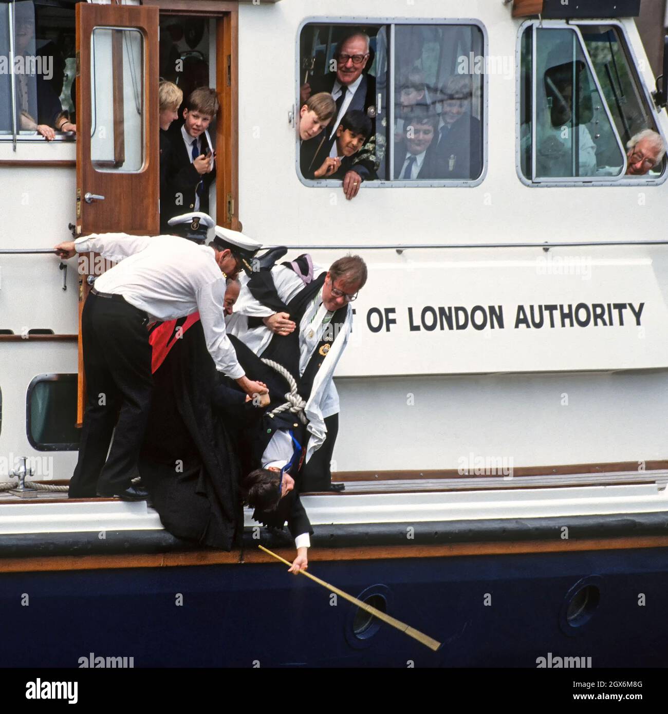Gros plan sur l'historique des années 1990, vue d'archives de l'ancienne coutume et tradition de battre les Bounds réalisée en 1992Par église de tous les Halles à la Tour avec l'aide du clergé de l'église et des garçons de l'école St Dunstan's CollegeEt le personnel est assisté par l'équipage de l'ALP pour tenir un garçon à l'envers par corde depuis un port de Londres des années 90Le lancement de l'autorité pour battre la frontière sud dans l'eau de rivière avec une canne un événement inhabituel au milieu deRiver Thames une image d'archives dans la ville de Londres Angleterre Royaume-Uni Banque D'Images