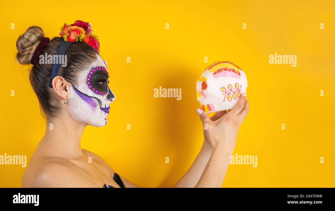 Catrina mexicaine, portrait d'une jeune femme latine tenant une calaverita de sucre ou un squelette sucré pour la fête d'Halloween au Mexique Banque D'Images