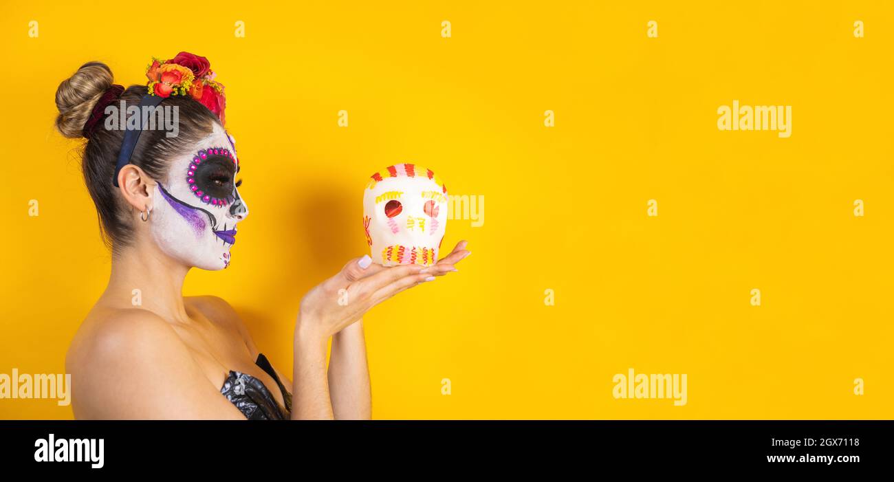 Catrina mexicaine, portrait d'une jeune femme latine tenant une calaverita de sucre ou un squelette sucré pour la fête d'Halloween au Mexique Banque D'Images