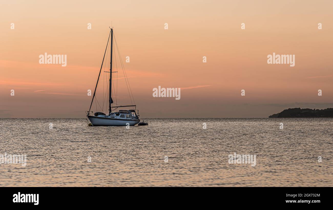 Un voilier est à l'ancre au coucher du soleil et un homme est debout dans une fenêtre dans la poupe, Vejle, Danemark, 4 septembre 2021 Banque D'Images