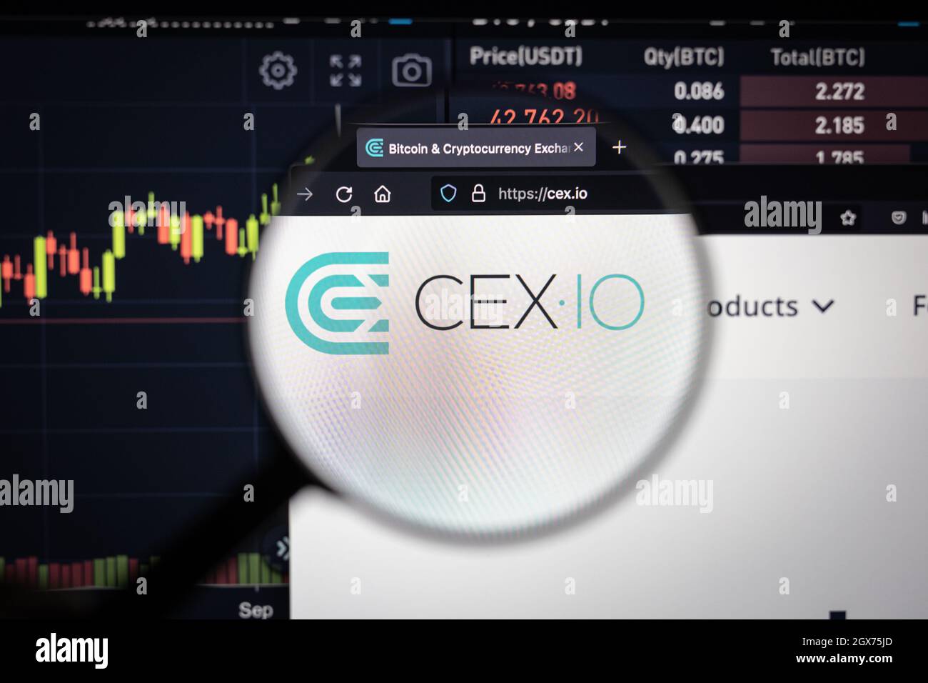LE logo de la société CEX.IO sur un site Web avec des développements flous du marché boursier en arrière-plan, vu sur un écran d'ordinateur à travers une loupe Banque D'Images