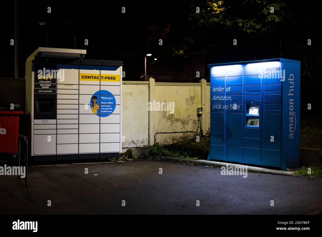 Casier de collecte de colis InPost et casier Amazon Hub vu la nuit dans le parking de la gare de Kenley, dans le sud de Londres. Banque D'Images