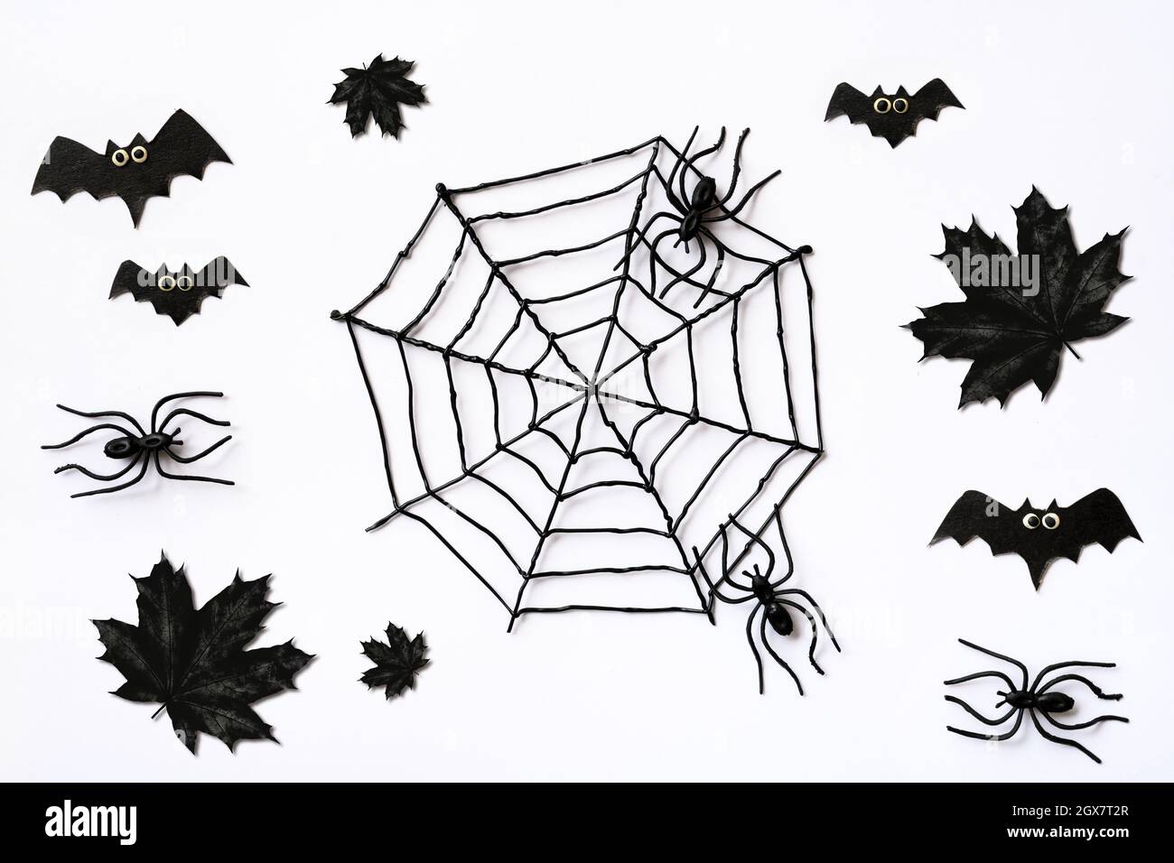 Motif Halloween avec feuilles d'érable noir, araignées et chauves-souris. Sinistre plat sur fond blanc pour la fête d'Halloween, décoration créepy pour Hallow Banque D'Images