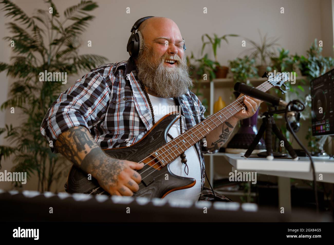 Un guitariste joyeux avec surpoids joue de la musique en enregistrant de nouvelles chansons dans son studio Banque D'Images