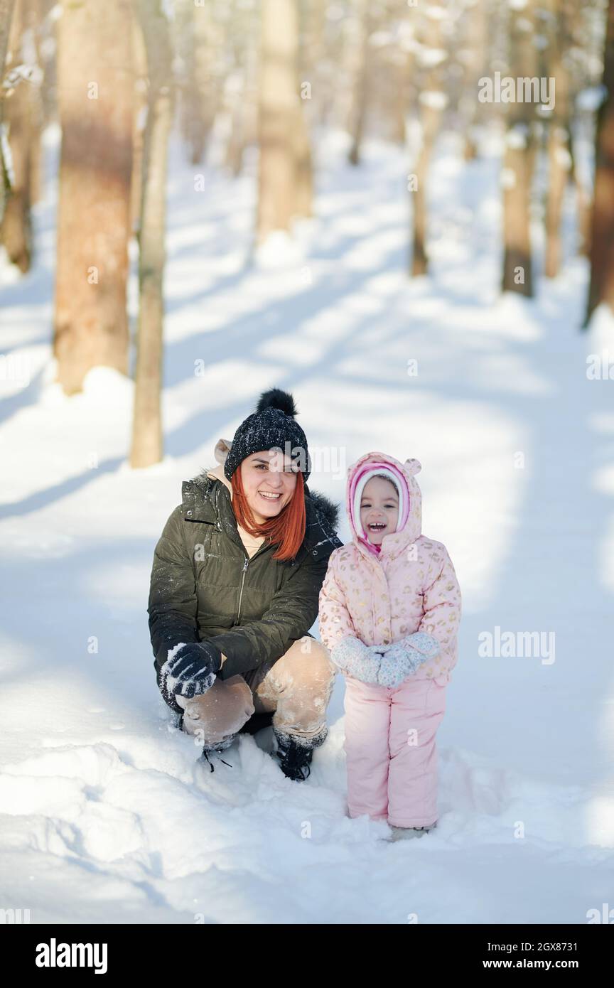 Détente en famille sur le thème du parc d'hiver. Portrait d'une femme avec un enfant sur fond enneigé Banque D'Images