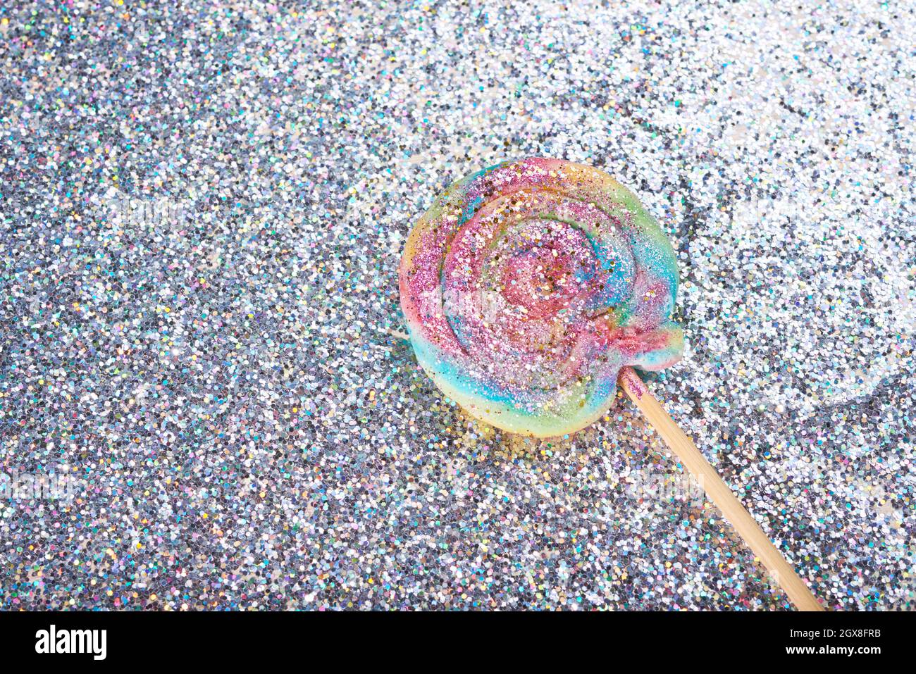 Gros plan de la boucle en toile de fond à motif de bonbon tourbillons arc-en-ciel sur fond de paillettes Banque D'Images