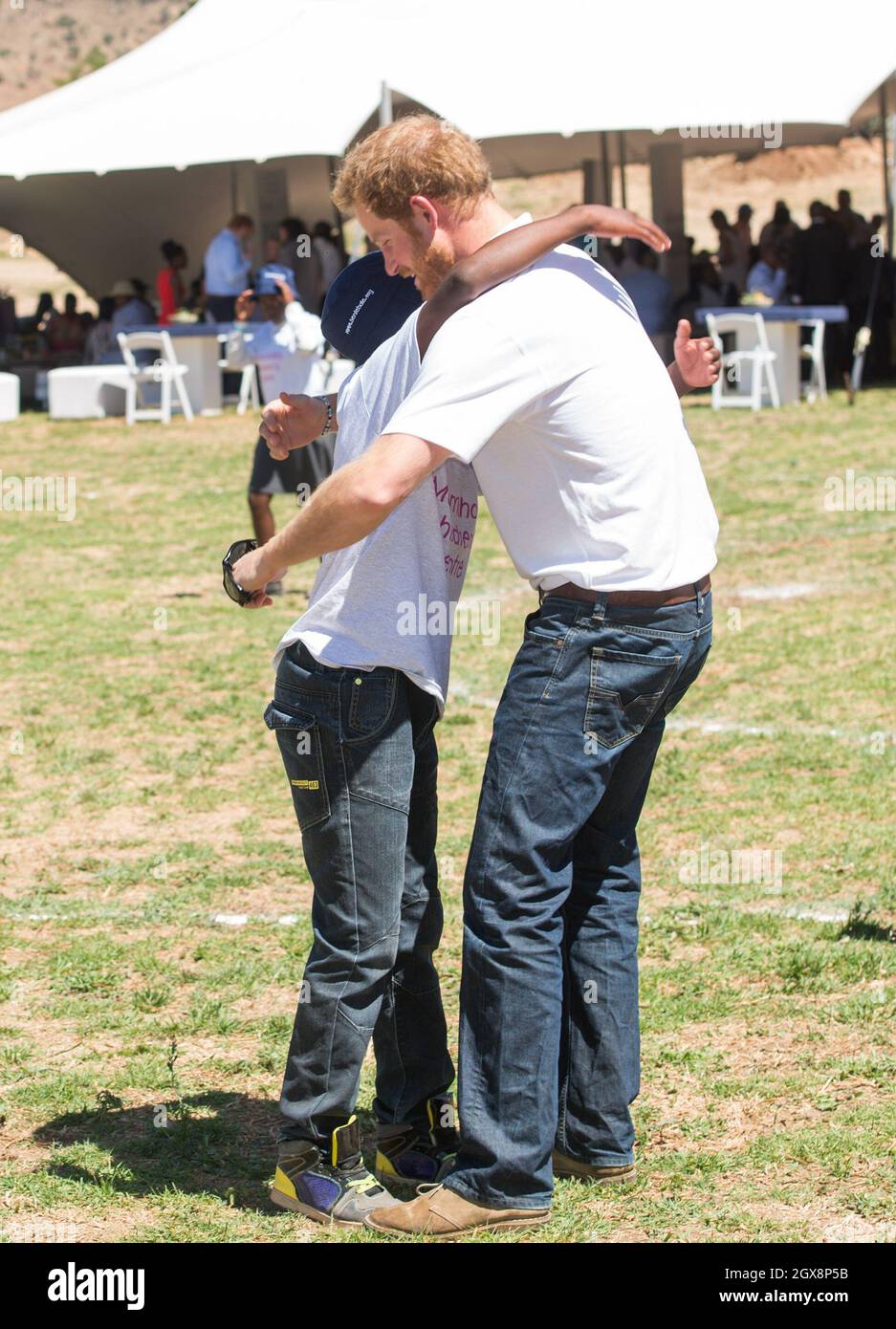 Le prince Harry salue son vieil ami Mutsu Potsane, aujourd'hui âgé de 15 ans, avec un câlin dans le parc du Centre pour enfants Mamohatho pour enfants atteints du VIH et du sida lors d'une visite de retour au Lesotho en Afrique australe le 26 novembre 2015.Au cours de la visite, le prince a parlé avec amour de la perte de sa mère, Diana, la princesse de Galles et du « trou béant » qu'il avait laissé dans sa vie. Banque D'Images