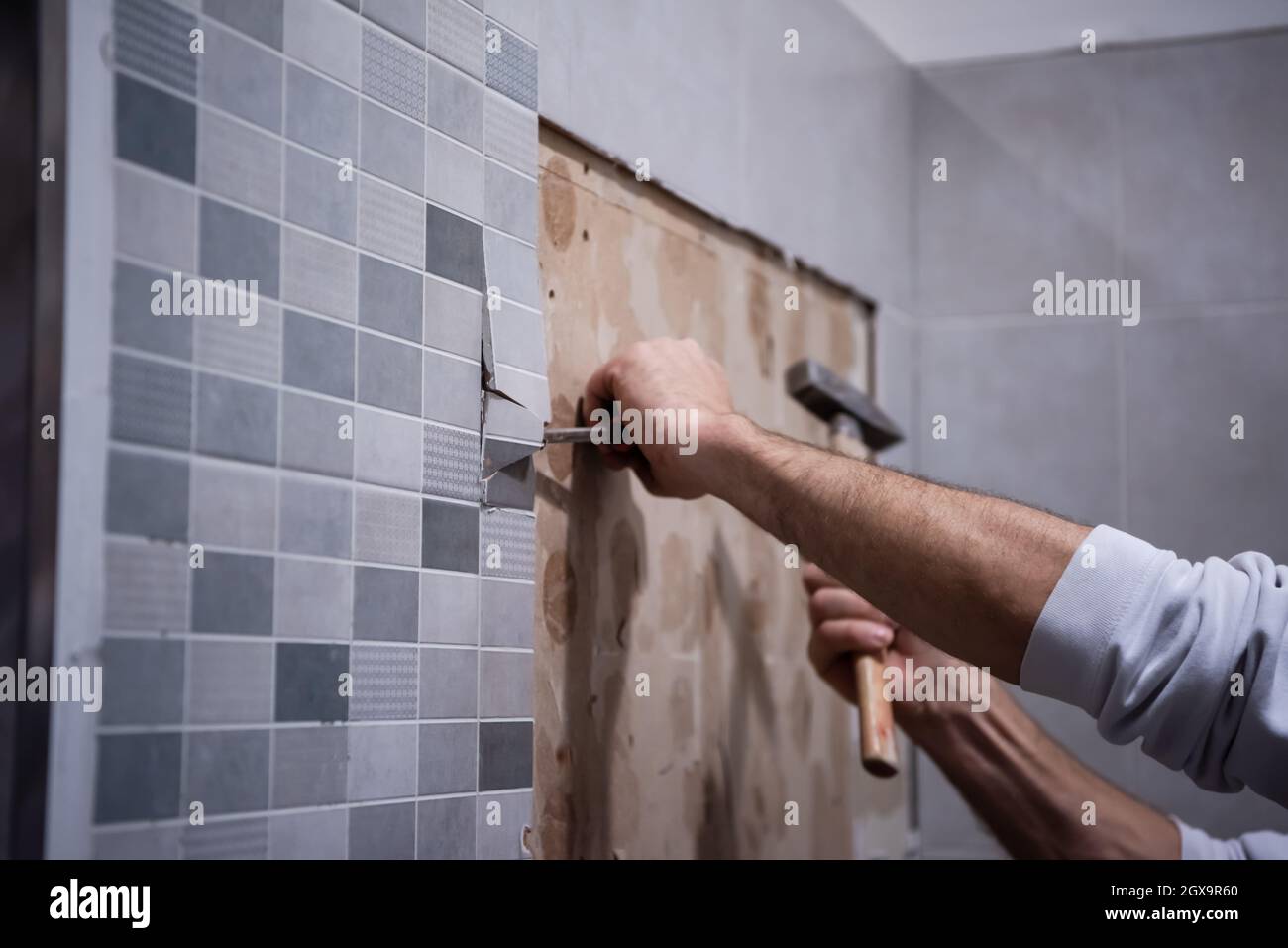 le travailleur professionnel enlève démolir les vieux tuiles dans une salle de bains avec marteau et burin Banque D'Images