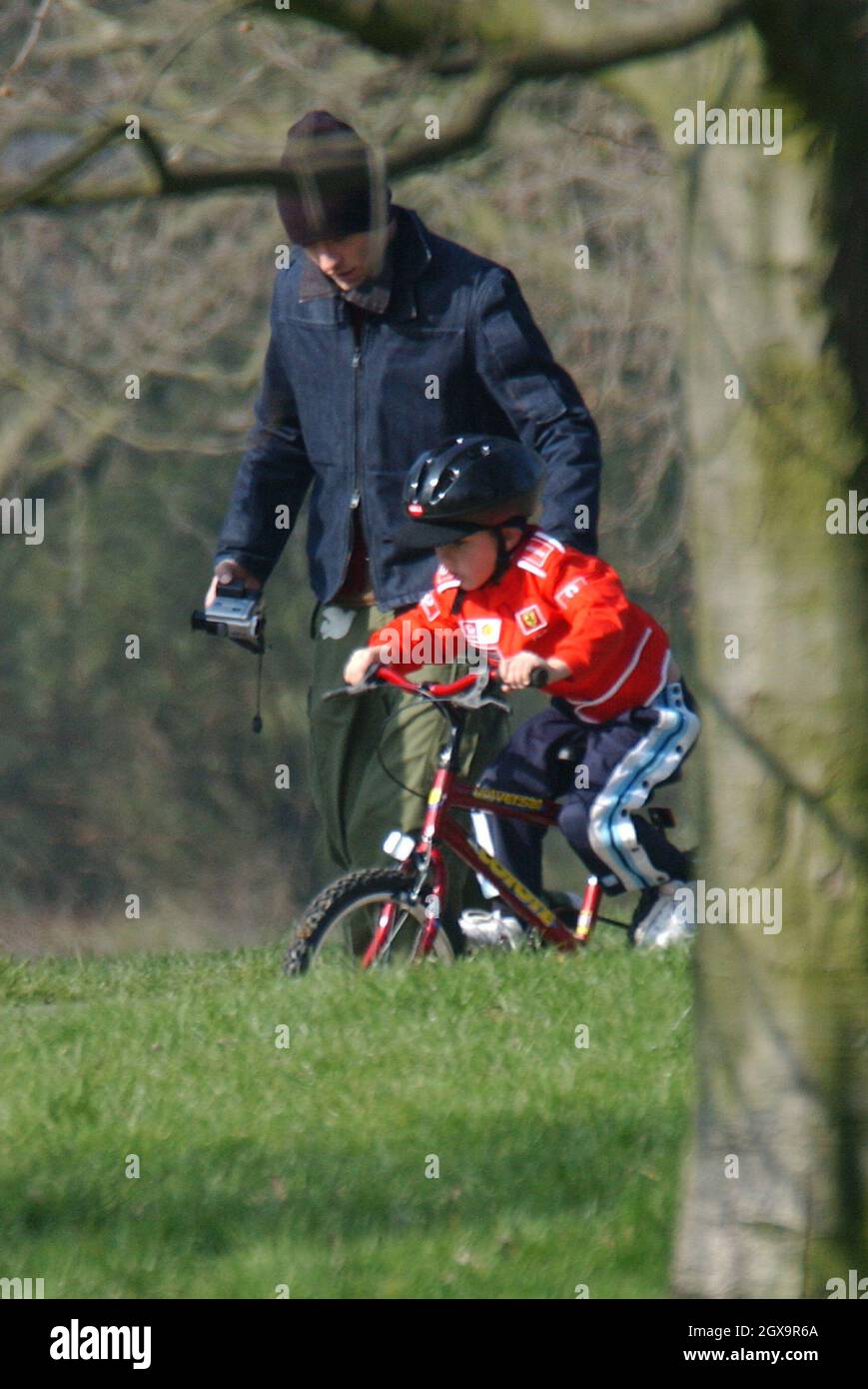 Jude Law y enseigne aux plus jeunes comment faire un vélo et Sadie avec les autres enfants jouant sur le swing et voir-vu. Banque D'Images