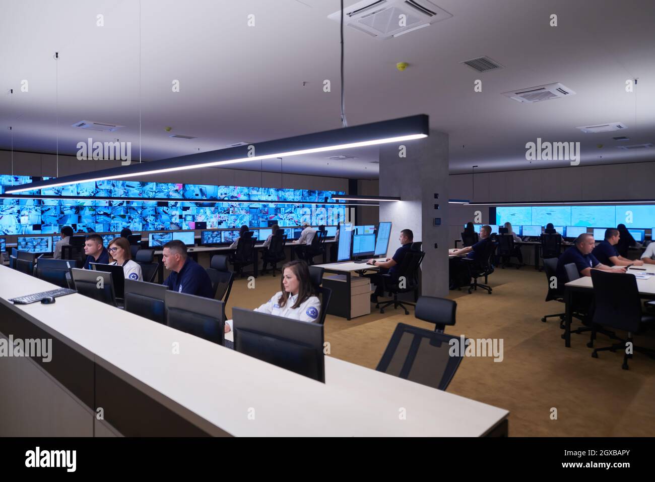 Groupe d'opérateurs de centre de données de sécurité travaillant dans une salle de surveillance CCTV regardant sur plusieurs moniteurs officiers surveillant plusieurs écrans pour Suspi Banque D'Images