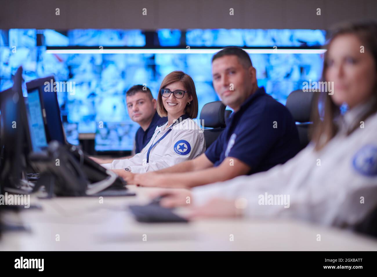 Groupe d'opérateurs de centre de données de sécurité travaillant dans une salle de surveillance CCTV regardant sur plusieurs moniteurs officiers surveillant plusieurs écrans pour Suspi Banque D'Images