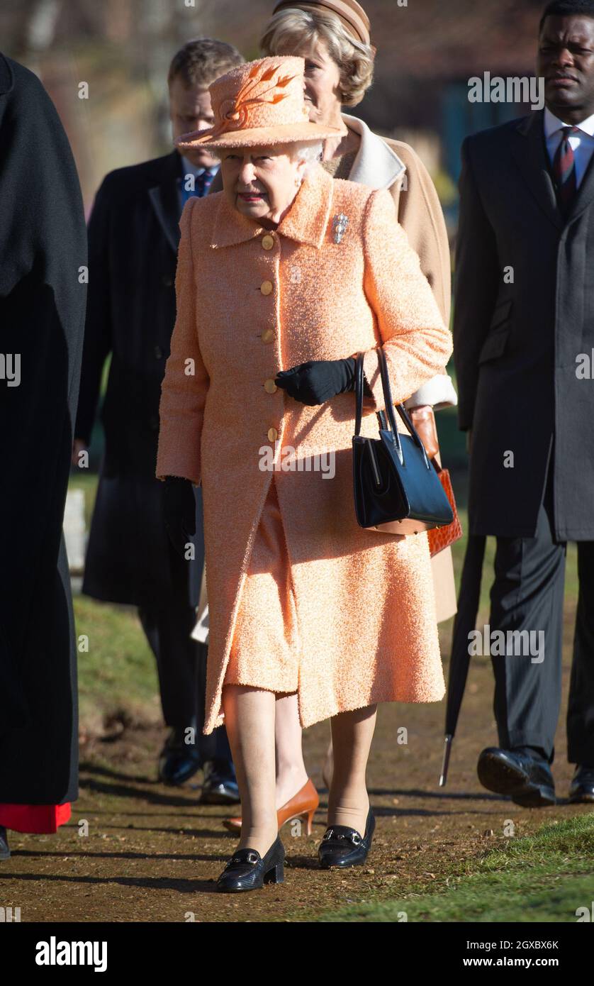 La reine Elizabeth ll, portant un manteau de laine de pêche et un chapeau assorti , assiste à un service d'église le dimanche matin à l'église St Pierre et St Paul à West Newton sur le domaine de Sandringham Banque D'Images