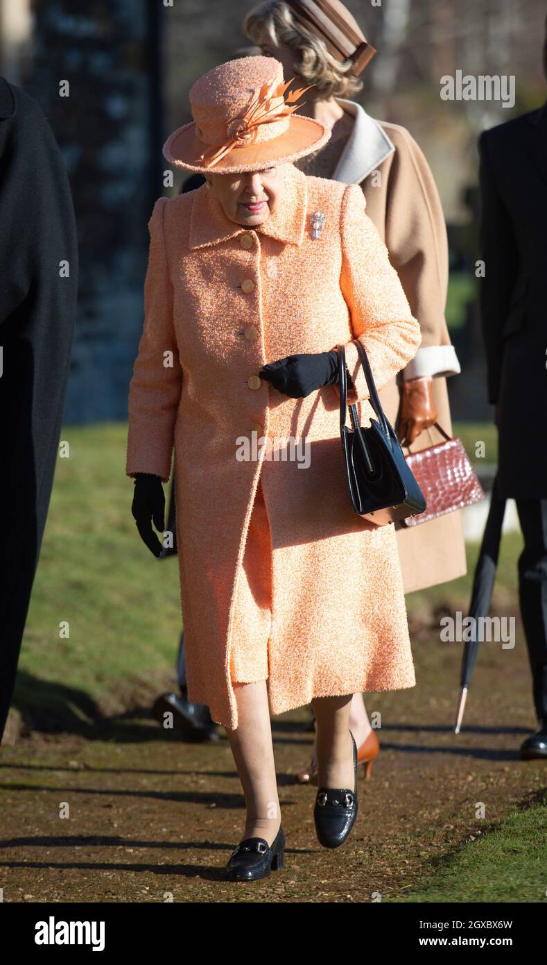 La reine Elizabeth ll, portant un manteau de laine de pêche et un chapeau assorti , assiste à un service d'église le dimanche matin à l'église St Pierre et St Paul à West Newton sur le domaine de Sandringham Banque D'Images